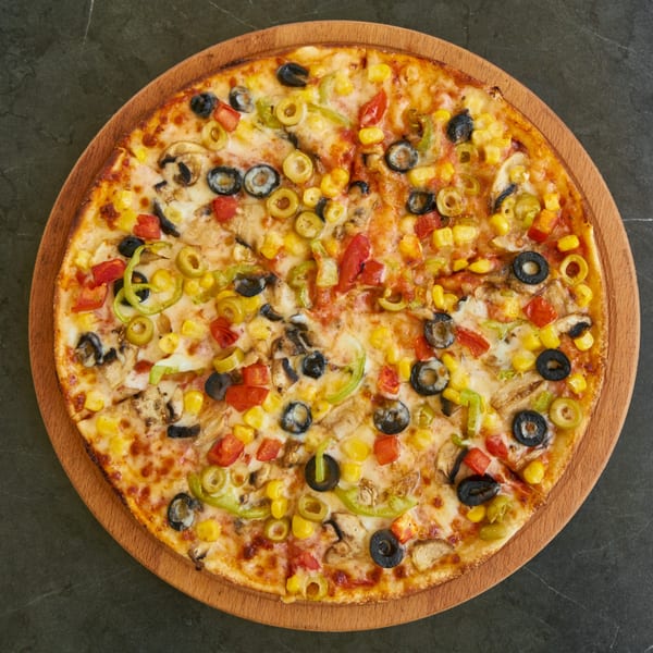 A vibrant Fox Point pizzeria pizza, loaded with olives, corn, peppers, and mushrooms on a wooden board.