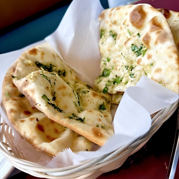 A basket of freshly baked naan bread with herbs, served at Spice Hub & Fox Point Pizzeria.