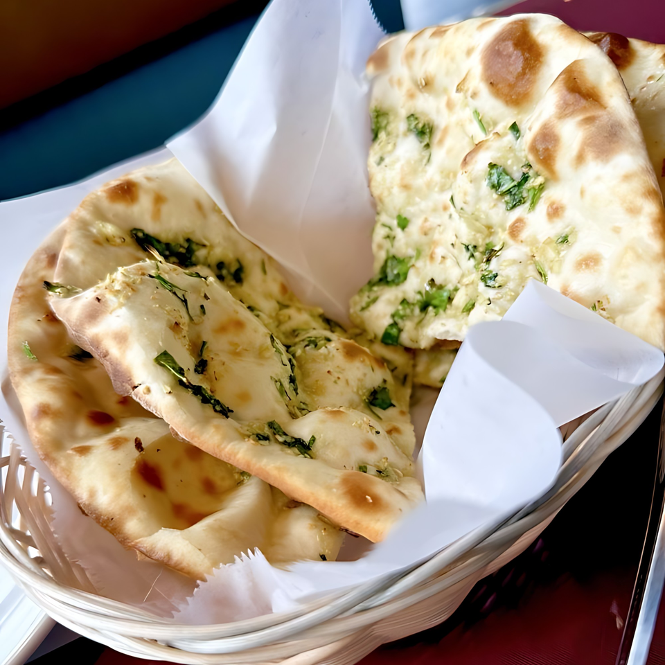 A basket of freshly baked naan bread with herbs, served at Spice Hub & Fox Point Pizzeria.